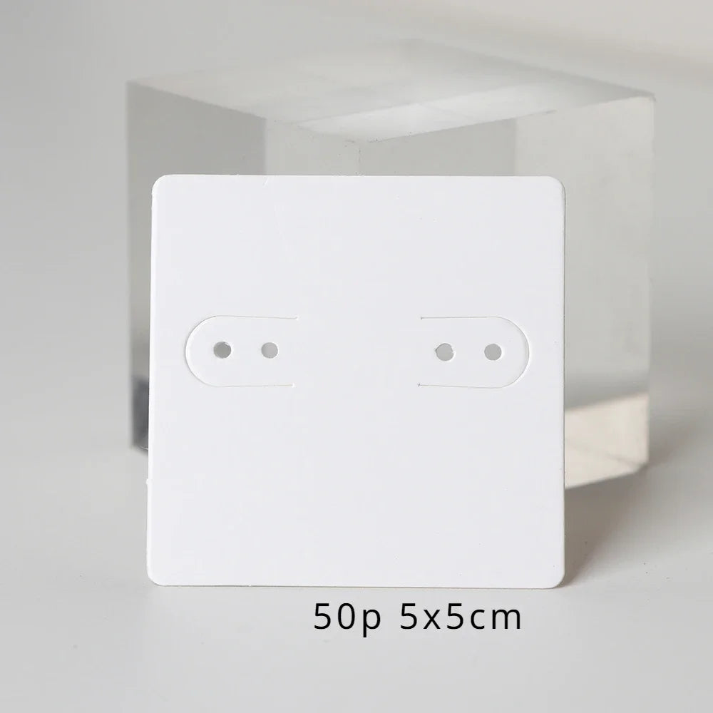 A white square jewelry display card with two oval holes is shown against a clear background.