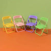 A set of five mini rubber duck accessories in yellow, pink, purple, and green sitting on an orange surface.