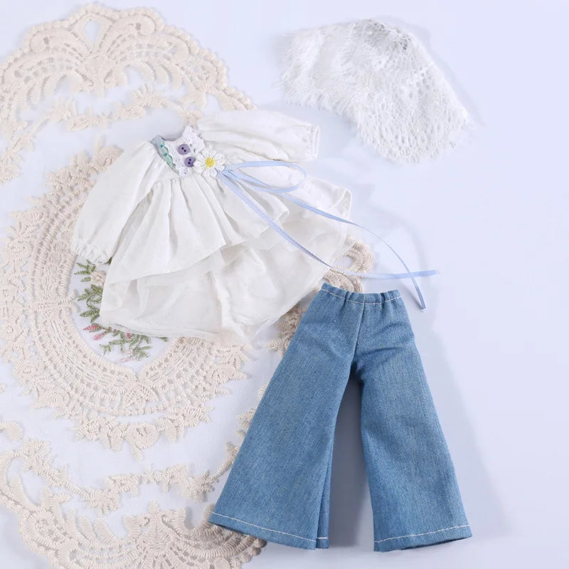 A white princess dress outfit set for a doll featuring a ruffled top, blue ribbon details, and denim pants.