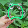 Una mano sostiene un tambor de percusión verde brillante con cascabeles plateados contra un fondo desenfocado de follaje verd