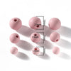 A collection of matte pink acrylic round beads with varying diameters and holes, shown against a white background.