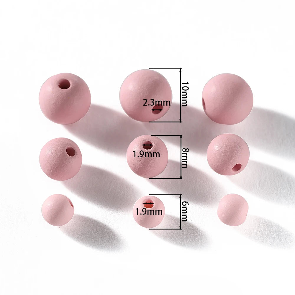 A collection of matte pink acrylic round beads with varying diameters and holes, shown against a white background.