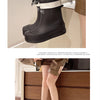 A pair of black waterproof mid-calf rain boots with white trim and non-slip soles shown on a person's leg.