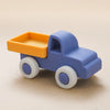 A blue cartoon car shaped silicone baby teether toy with an orange cargo bed and white wheels.