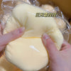 Hände drücken einen großen, blassgelben, quetschbaren Stressball-Fidget-Spielzeug in durchsichtige Plastikverpackung.