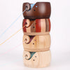 A stack of handcrafted wooden yarn bowls featuring swirl cutout designs in various natural wood tones.