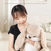 A woman is holding a large, light brown and white plush rabbit toy.