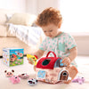 A toddler is playing with a red wooden farm animal toy set featuring various plush animals and sensory elements.