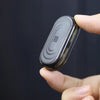 A hand holds a black EDC push slider fidget toy with a textured surface against a dark background.