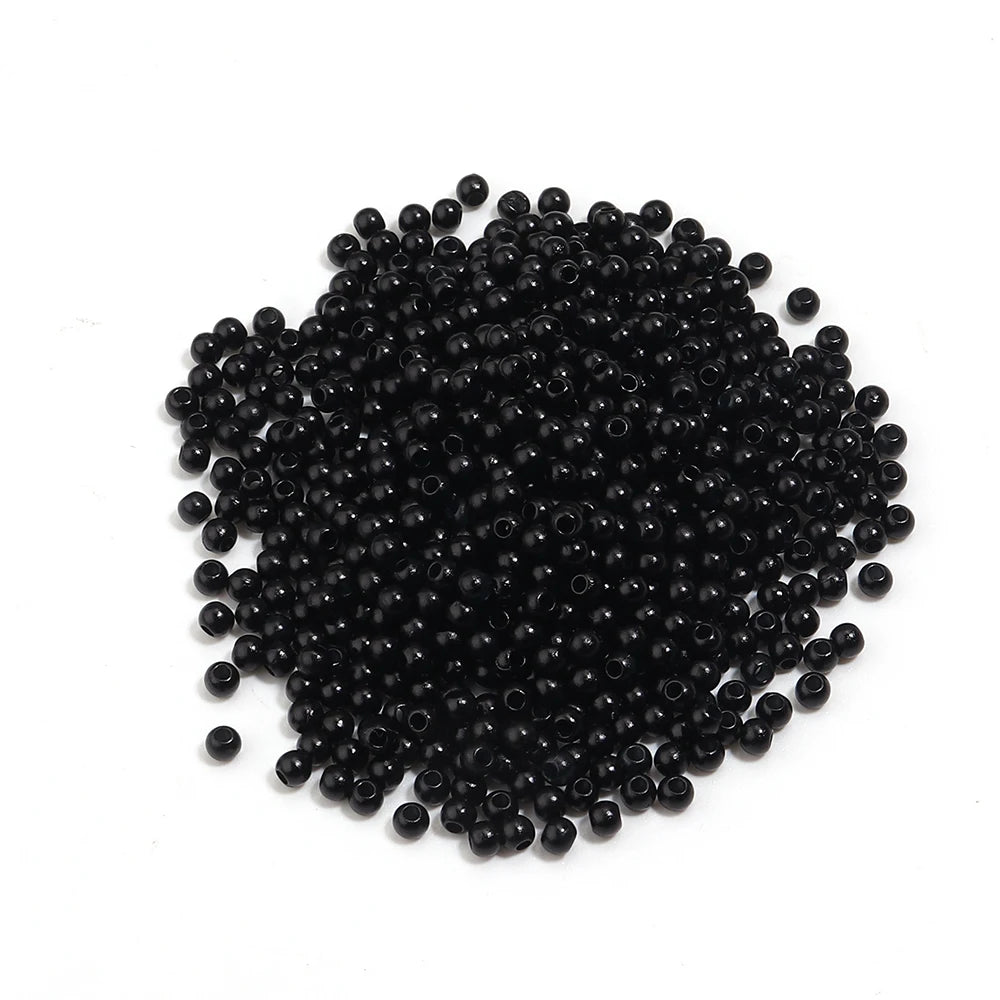 A pile of small, black, round imitation pearl beads for jewelry making.