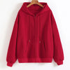 A maroon oversized zip-up hoodie hanging on a wooden hanger against a white wall.