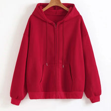 A maroon oversized zip-up hoodie hanging on a wooden hanger against a white wall.