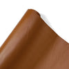 A close-up view of a brown PU leather self-adhesive repair patch rolled up.