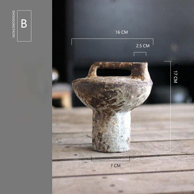 A vintage handcrafted ceramic vase with a textured, earthy brown color is shown on a wooden surface.