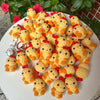 A pile of handmade crochet animal keychains in orange and yellow yarn on a white plate.