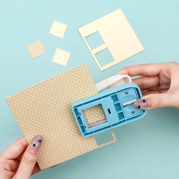 A hand holds a blue square postage stamp puncher and several yellow perforated stamps on a light blue background.