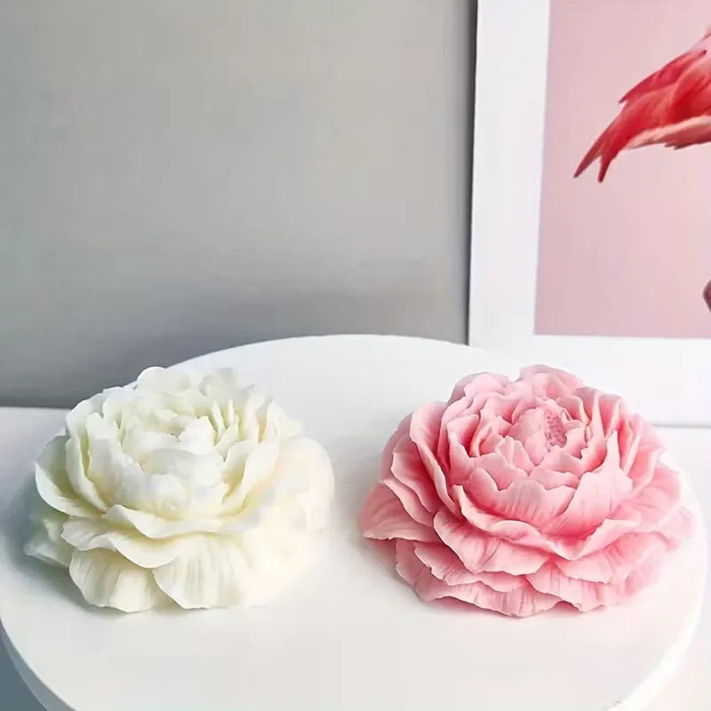 A white peony flower silicone mold next to a pink peony flower silicone mold on a white surface.