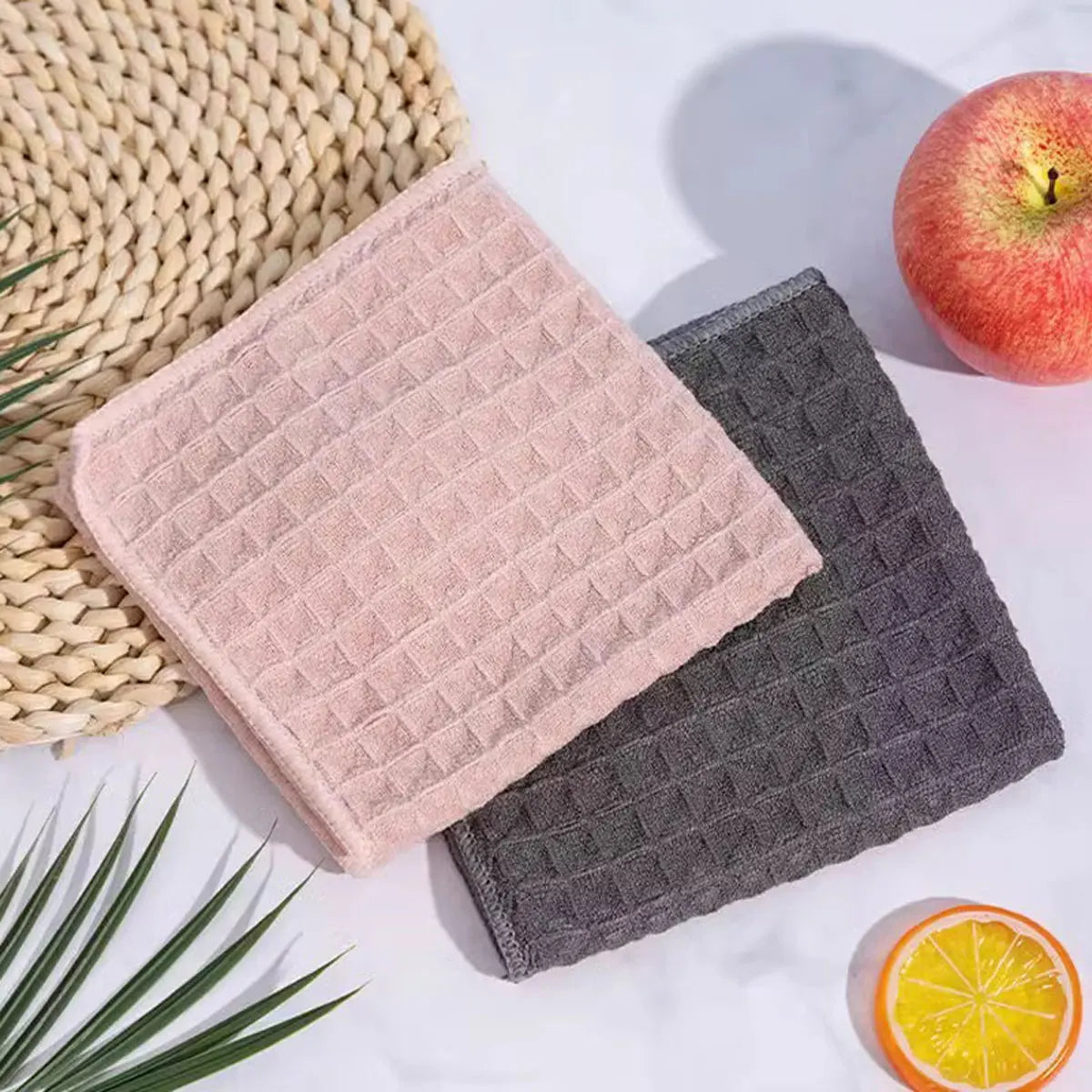 A stack of pink and gray microfiber kitchen cleaning cloths next to a lemon.