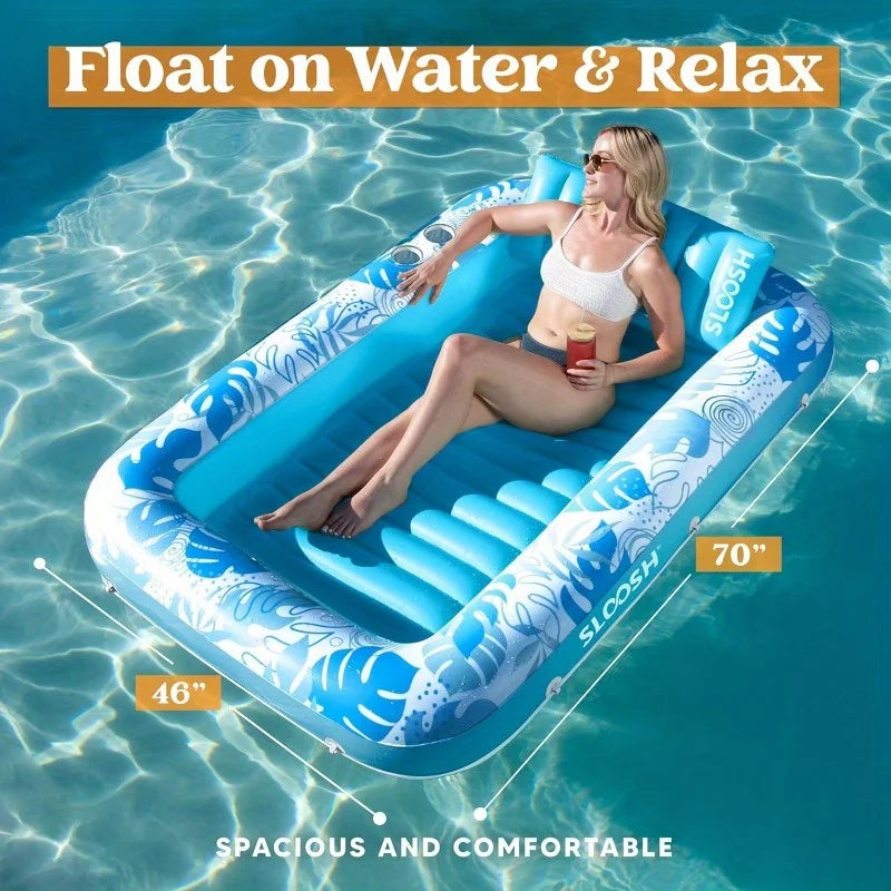 A woman relaxing on a blue inflatable float in clear water, demonstrating the spacious and comfortable design.