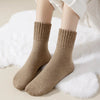 A pair of beige fleece-lined slouch socks lying on a white fluffy surface.