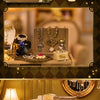 A detailed French-style wooden miniature dollhouse kit with intricate furniture and accessories displayed on a gold-colored f