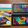 A box and an open plastic case of a pyramid bead logic puzzle with colorful beads.