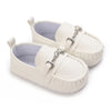 Pair of white baby first walker sneakers with a dinosaur print detail and silver hardware.
