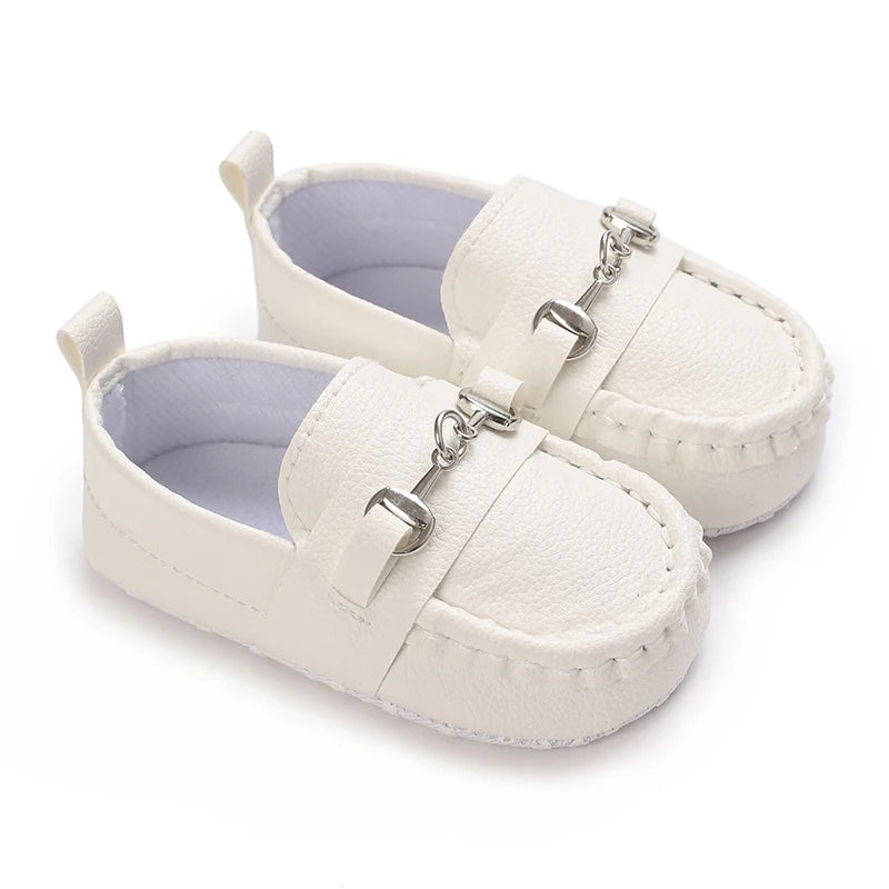 Pair of white baby first walker sneakers with a dinosaur print detail and silver hardware.