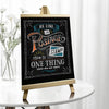 A wooden chalkboard easel displaying the phrase Be Like Postage Stick to One Thing until you get there