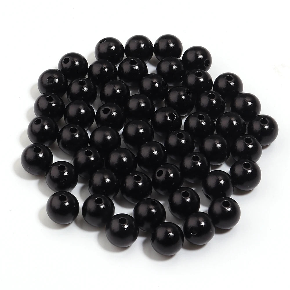 A pile of small, round, black imitation pearl beads for jewelry making.