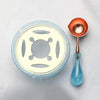 An elegant wax seal melting kit featuring a round silicone mold, a small copper spoon, and a glass heater.