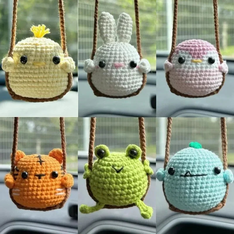 A collection of handmade crochet animal swing ornaments including a yellow duck, a white rabbit, a pink bird, an orange tiger