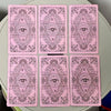 A set of pink Rider Waite Tarot cards featuring intricate designs and an eye motif.