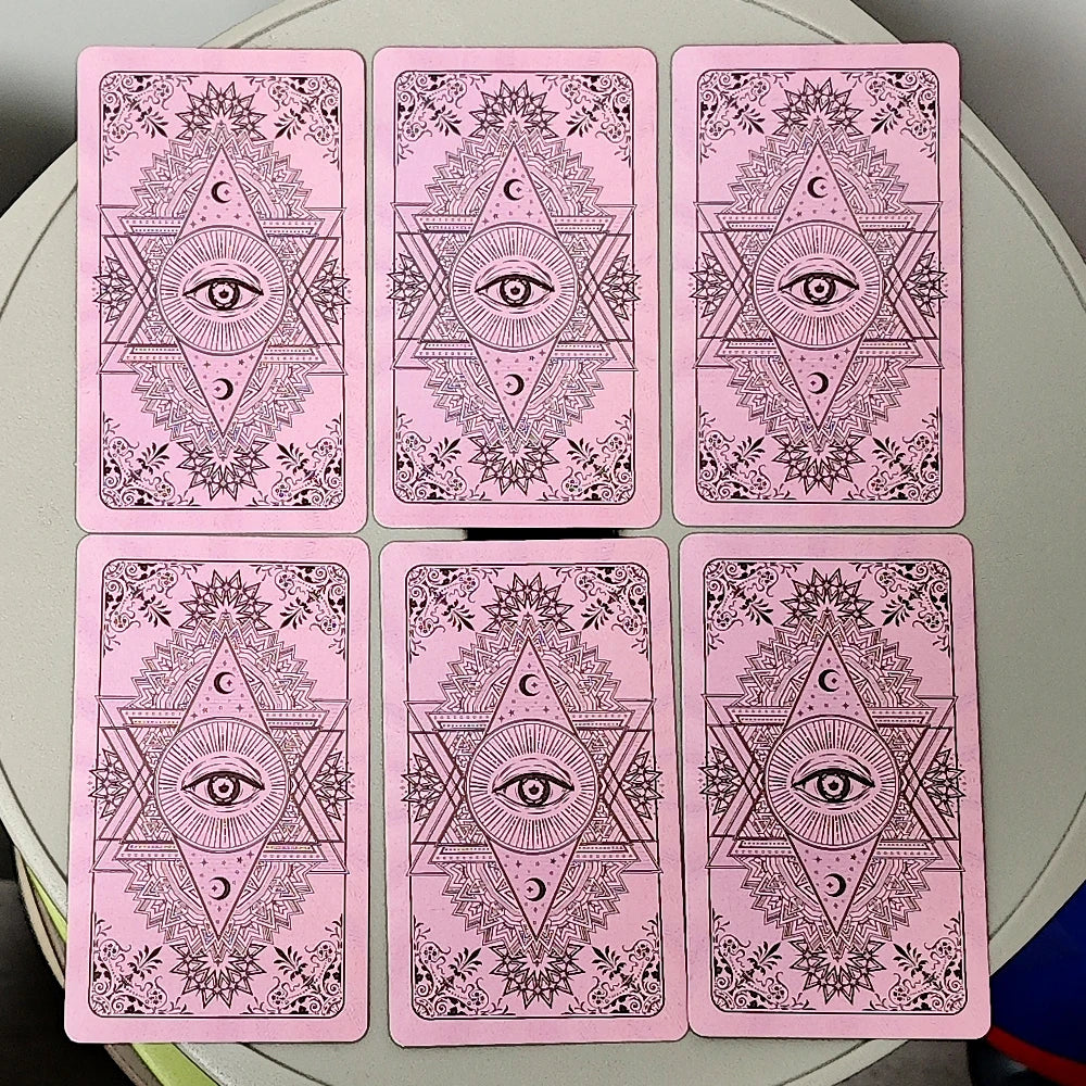 A set of pink Rider Waite Tarot cards featuring intricate designs and an eye motif.
