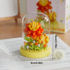 A clear glass dome showcases a colorful DIY flower bouquet built from small building blocks on a yellow base.
