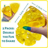 A hand holds a bright yellow honey cheese squishy stress ball, showing its texture and size relative to a finger.