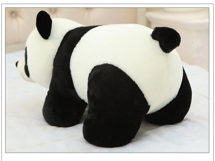 A white and black panda plush pillow resting on a white surface.