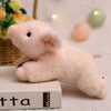 A soft pink plush pig stuffed animal lying on a white book.