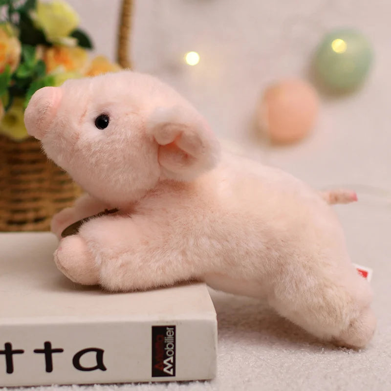 A soft pink plush pig stuffed animal lying on a white book.