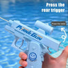 A hand holds a light blue water gun, ready to be pressed, with text instructing to press the rear trigger.