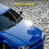 A close-up shot of a blue Nissan Skyline R34 RC drift car model with a glossy paint finish on asphalt.
