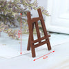 A small, brown wooden artist easel with measurements shown on a white surface.