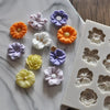 A collection of purple, orange, and white silicone flower molds for chocolate and cake decorating.