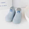 A pair of light blue knitted soft sole sock shoes for babies and toddlers with blue accents.