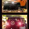 Close-up of an orange 1:18 scale RC Jeep showing bright headlight and rear lights in an off-road setting.