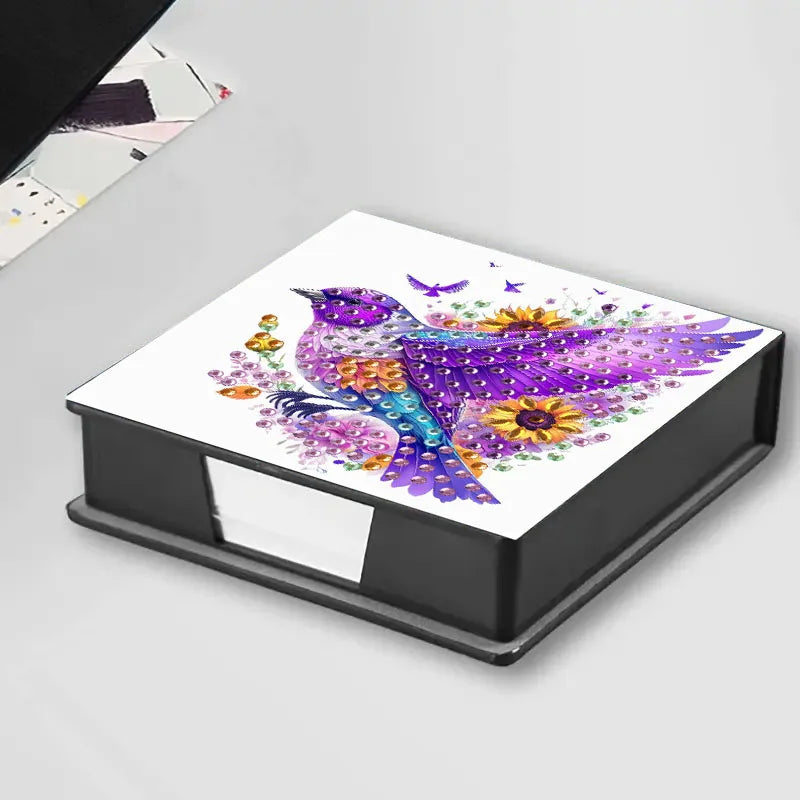 A DIY diamond painting animal pattern featuring a purple and blue bird on a white background inside a storage box.