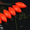 A row of bright orange oval fishing floats with attached bobber beads is displayed on a dark surface.