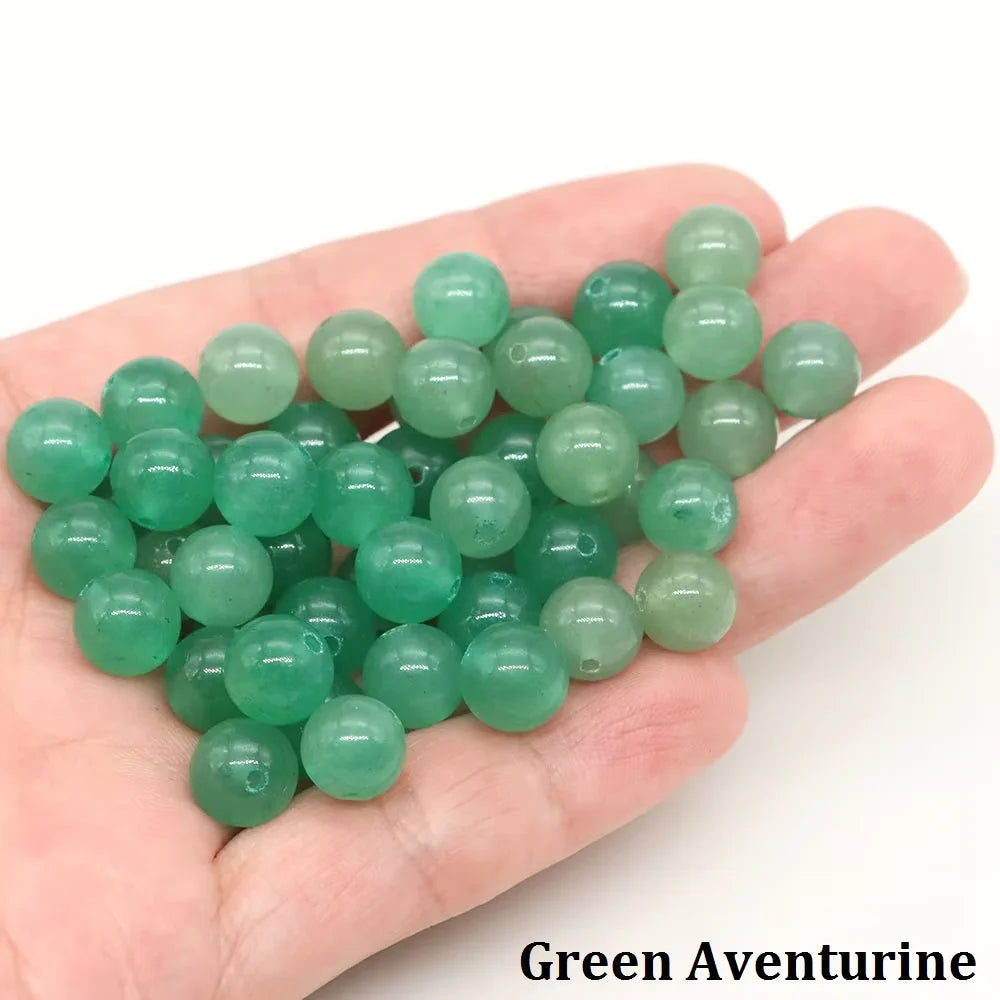 A handful of green aventurine round beads for jewelry making resting on a hand.