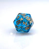 Ocean blue resin dice with gold foil numbers and dots, resting on a white surface.