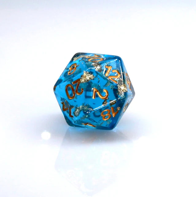Ocean blue resin dice with gold foil numbers and dots, resting on a white surface.